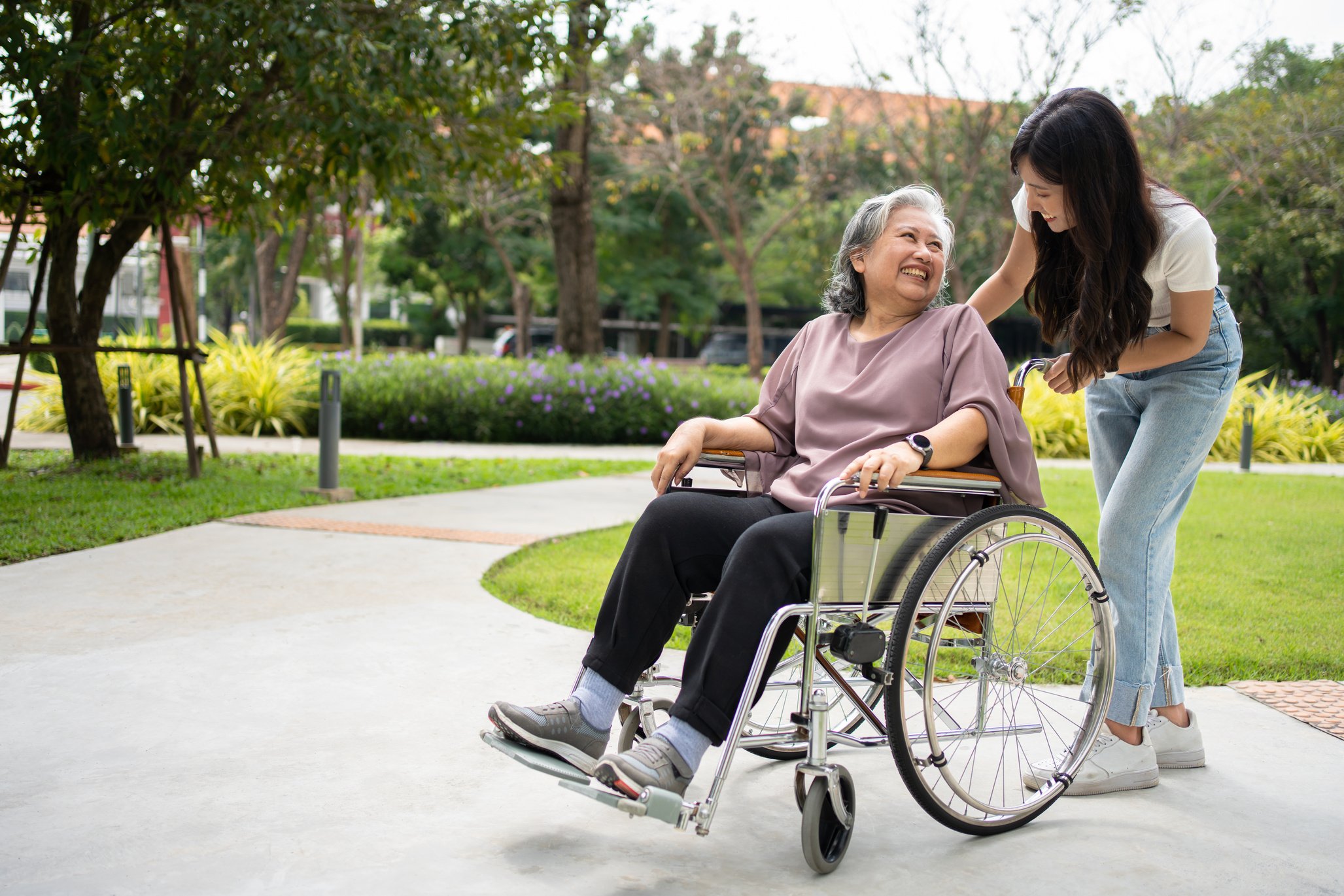 Asian careful caregiver or nurse taking care of the patient in a wheelchair. Concept of happy retirement with care from a caregiver and Savings and senior health insurance, a Happy family